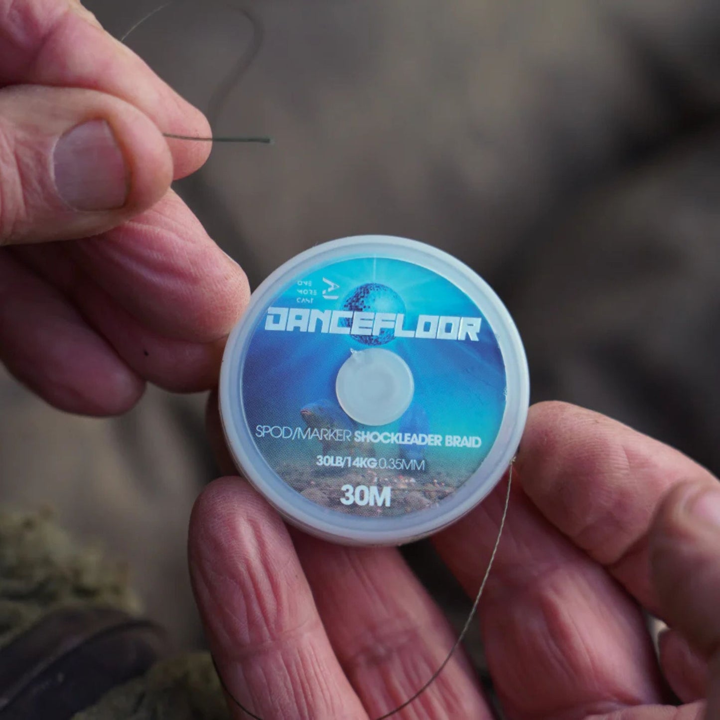 OMC Dancefloor Spod & Marker Shockleader Braid spool held in angler's hand with braid pulled off showing texture and colour