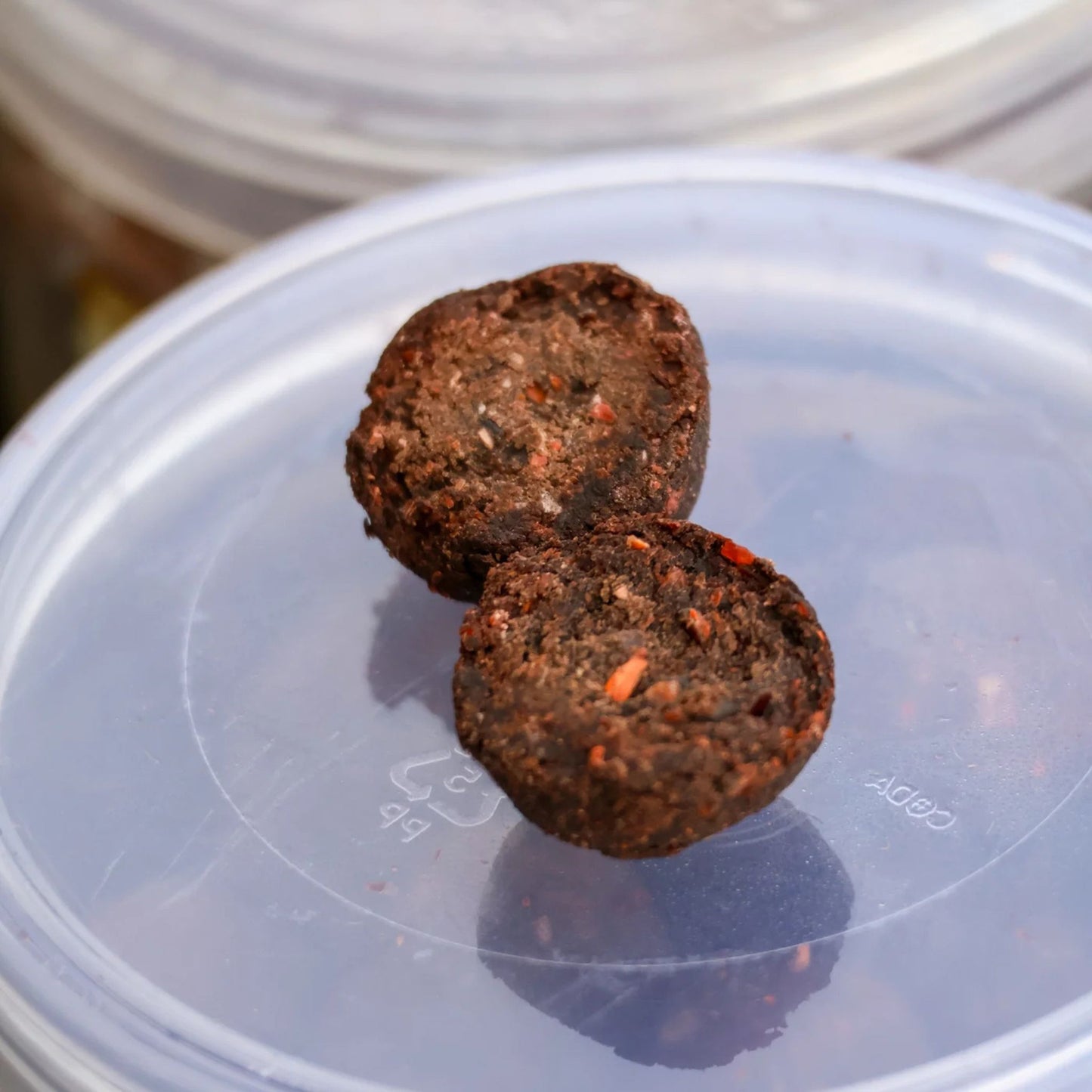 OMC Paella Boosted Cured Hookbait broken in half on tub lid showing hardened inner core and soluble outer crust